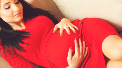 A pregnant woman in red rubbing her belly