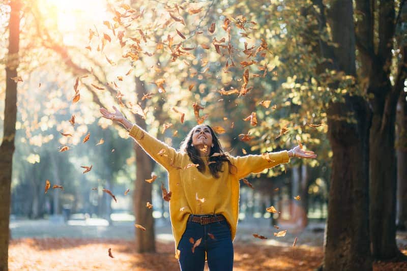woman throwing fall leaves in the air