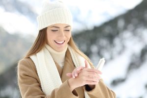 woman hydrating hands skin with moisturizer cream in a snowy mountain