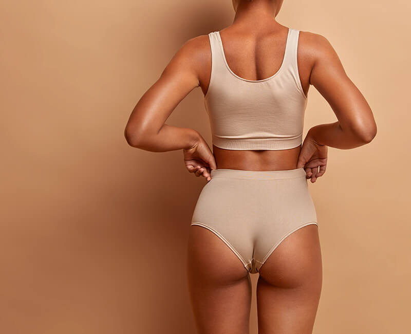 Backview of a woman in nude colored undergarments with voluptuous curves