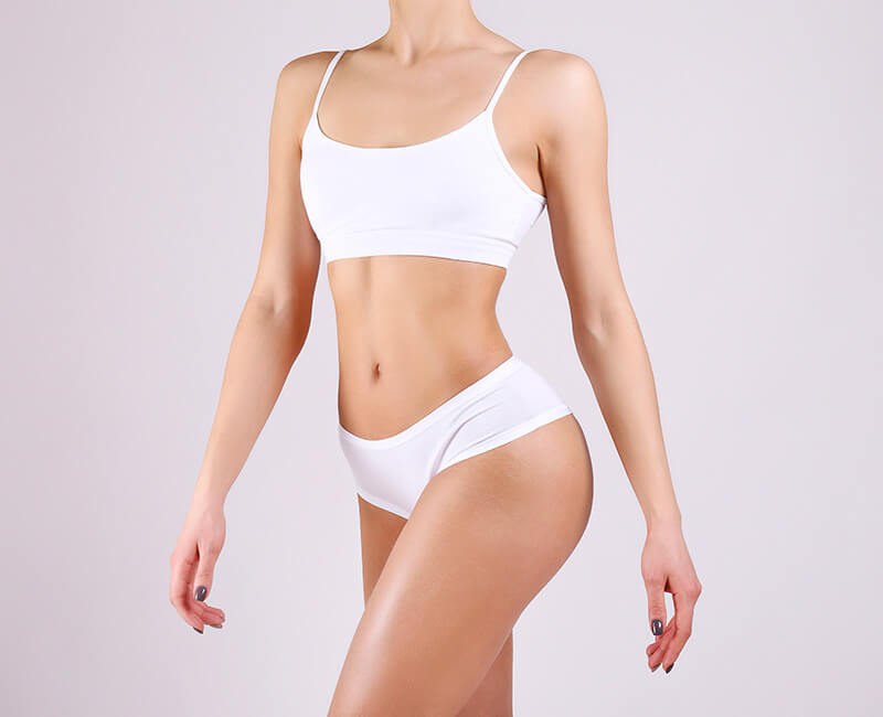 Mid body shot of a thin woman in white undergarments