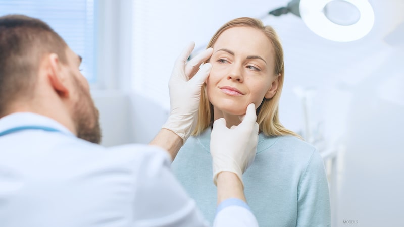 Woman undergoing a facial plastic surgery consultation with a doctor.
