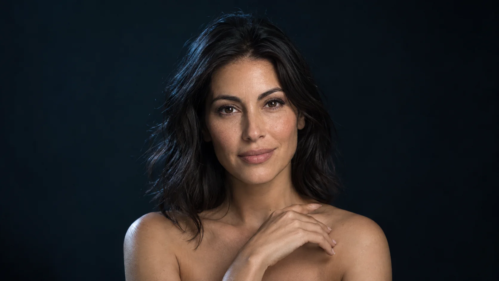 Woman with smooth, natural-looking skin against a dark background